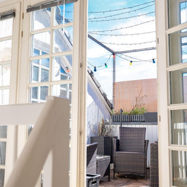 Blick durch französische Fenster auf die Terrasse einer Bonner Wohnung zum Verkauf mit bunten Lichterketten
